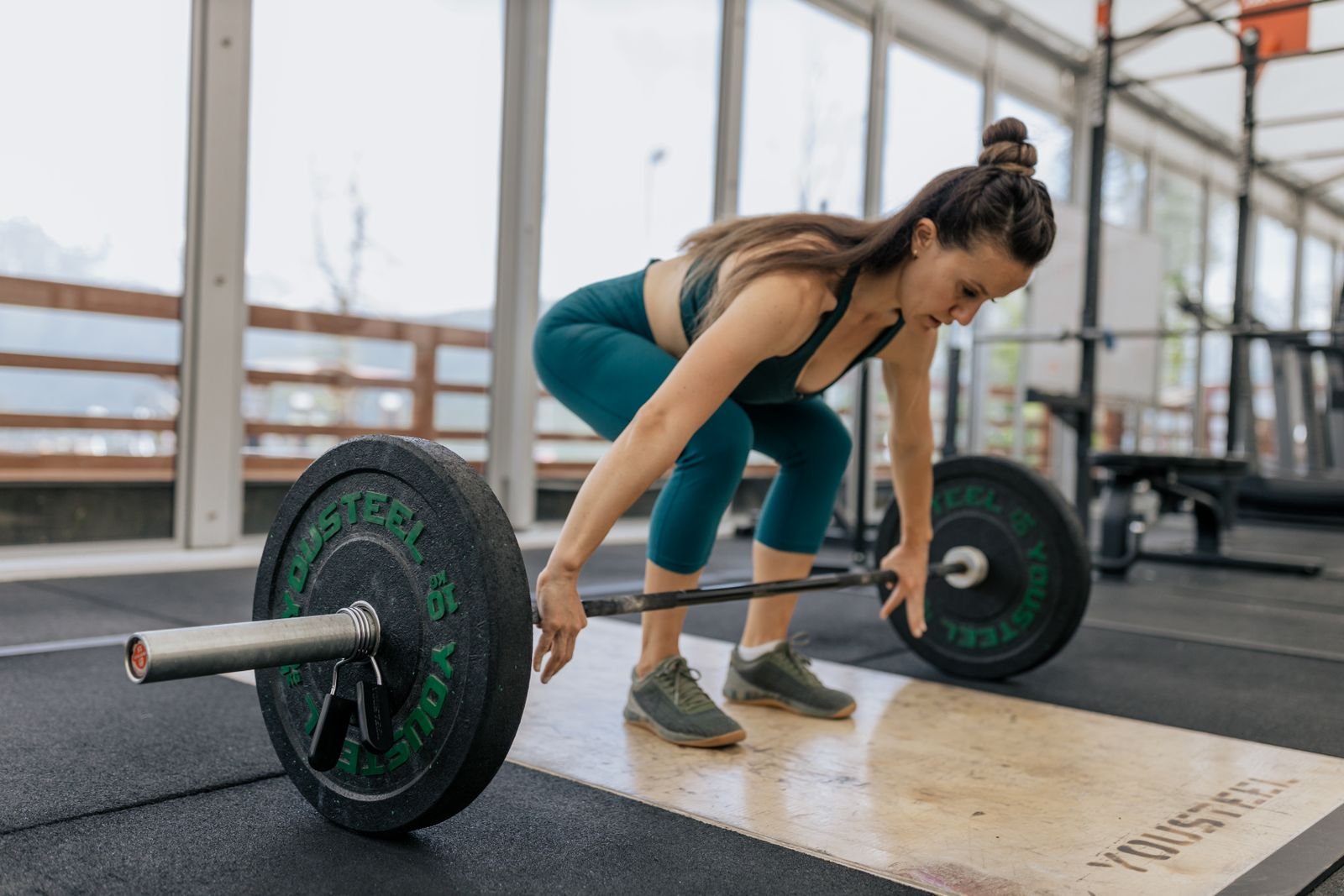 Atleta colocándose para un peso muerto, gimnasio luminoso.
